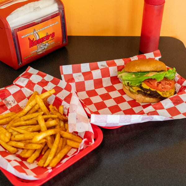 Romeo's Vegan Burgers meal with a burger, fries, and a red napkin dispenser on a table.